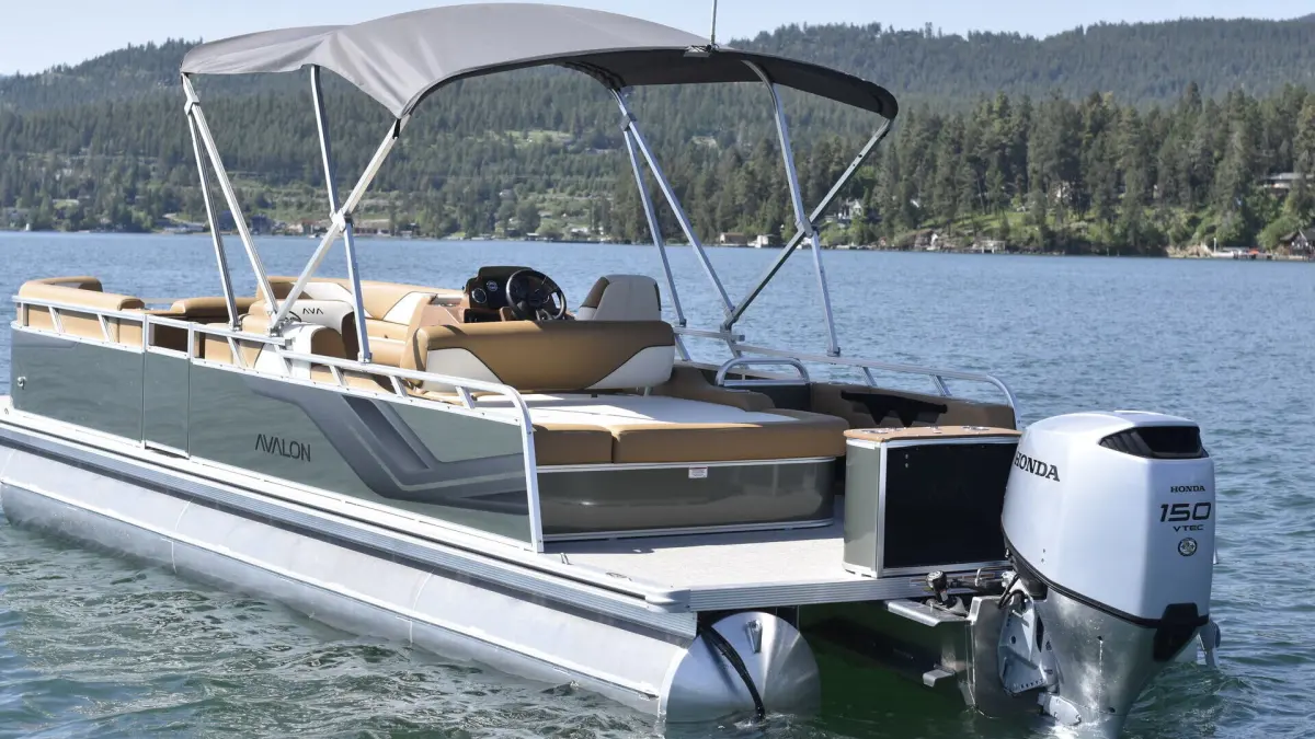 Pontoon boat with canopy on a lake, forested hills in background.