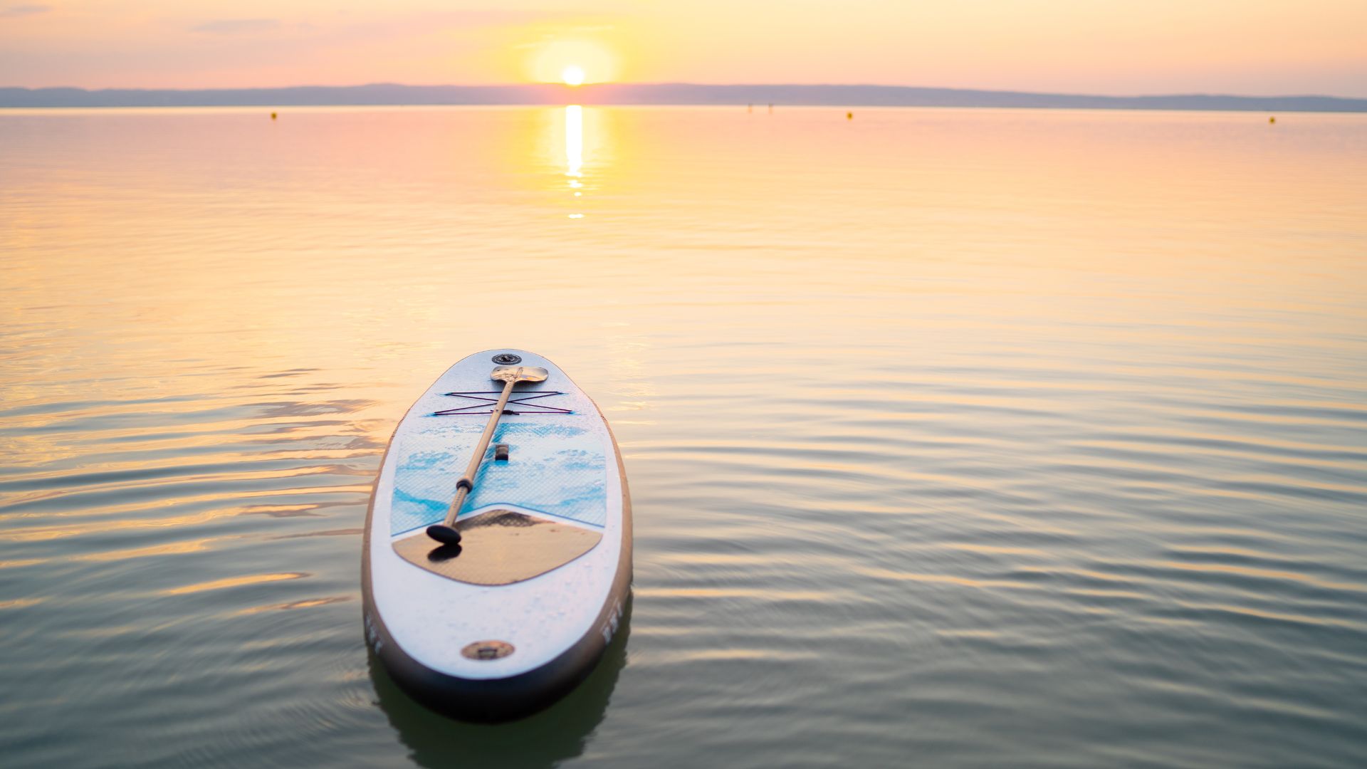 A standup paddleboard drifting on a lake at sunset