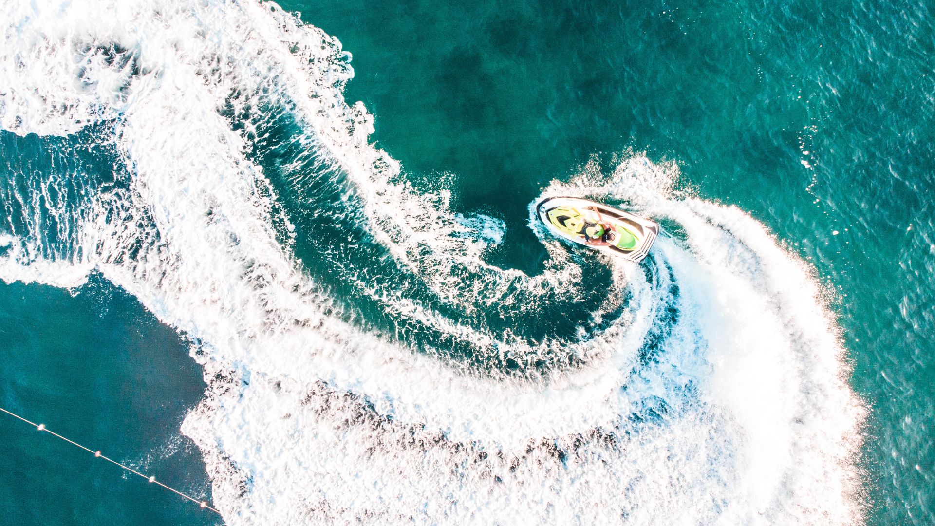 Aerial view of a jet ski making a circular pattern in turquoise water.