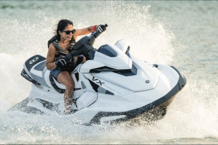Person riding a white jet ski on water, creating splashes.