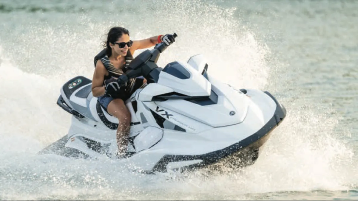 Person riding a white jet ski on water, creating splashes.