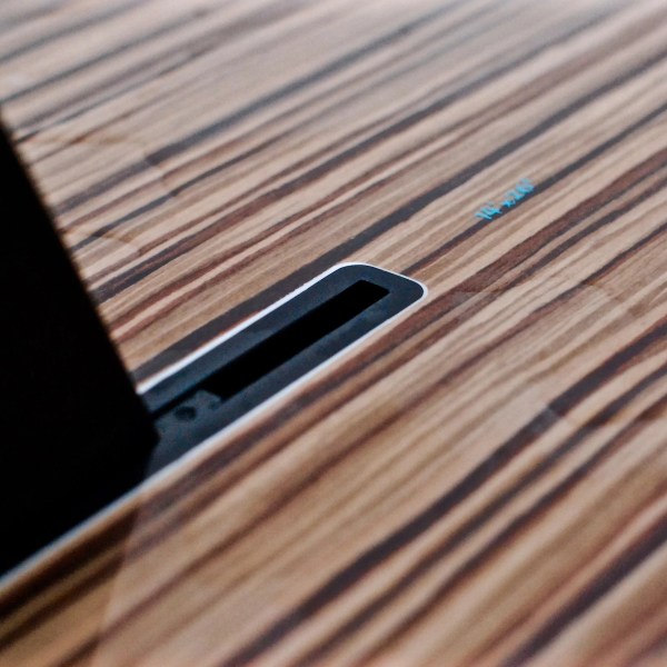 Close-up of a light wood grain surface with a black slot.