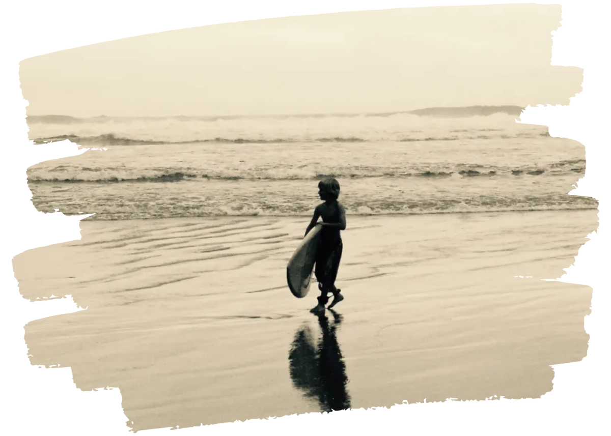 Child with a surfboard on a beach in sepia tone.